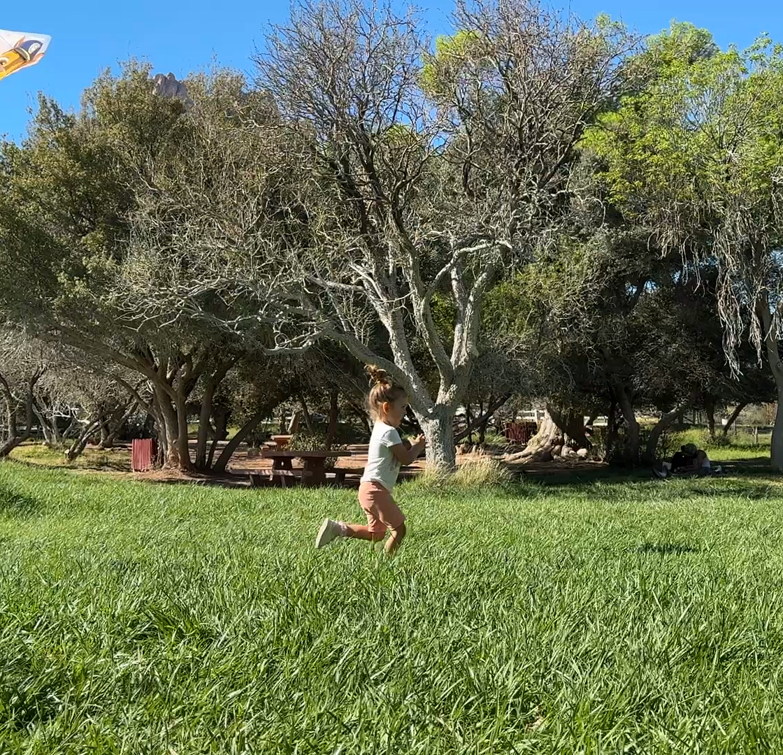 Child running in profile through a sunny park